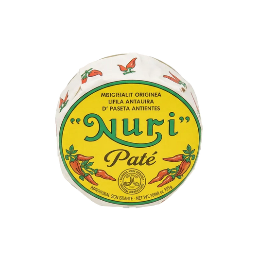 A round package of 'Nuri' Paté pepper paste, featuring a prominent yellow label with green and red text and illustrations of red chili peppers, set against a transparent checkerboard background.